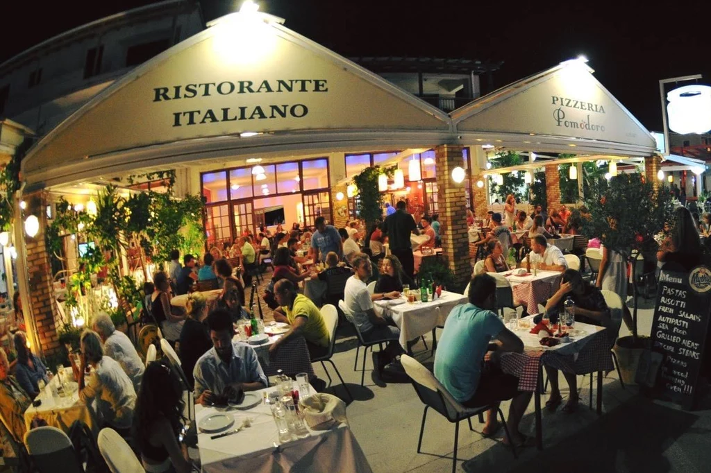 Pomodoro lit up at night with a full terrace